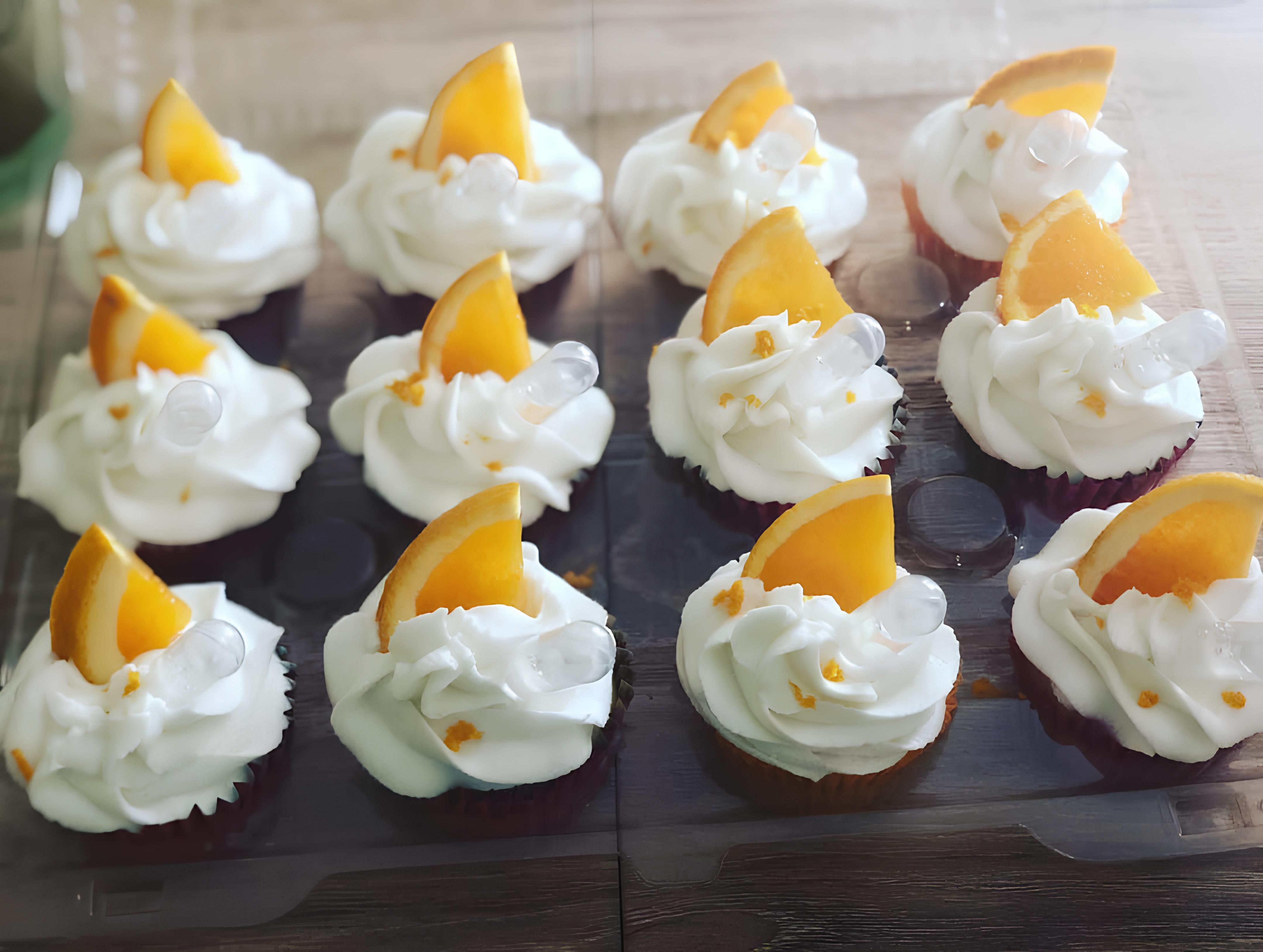 Orange-colored cupcake shooters topped with decadent frosting and orange slices